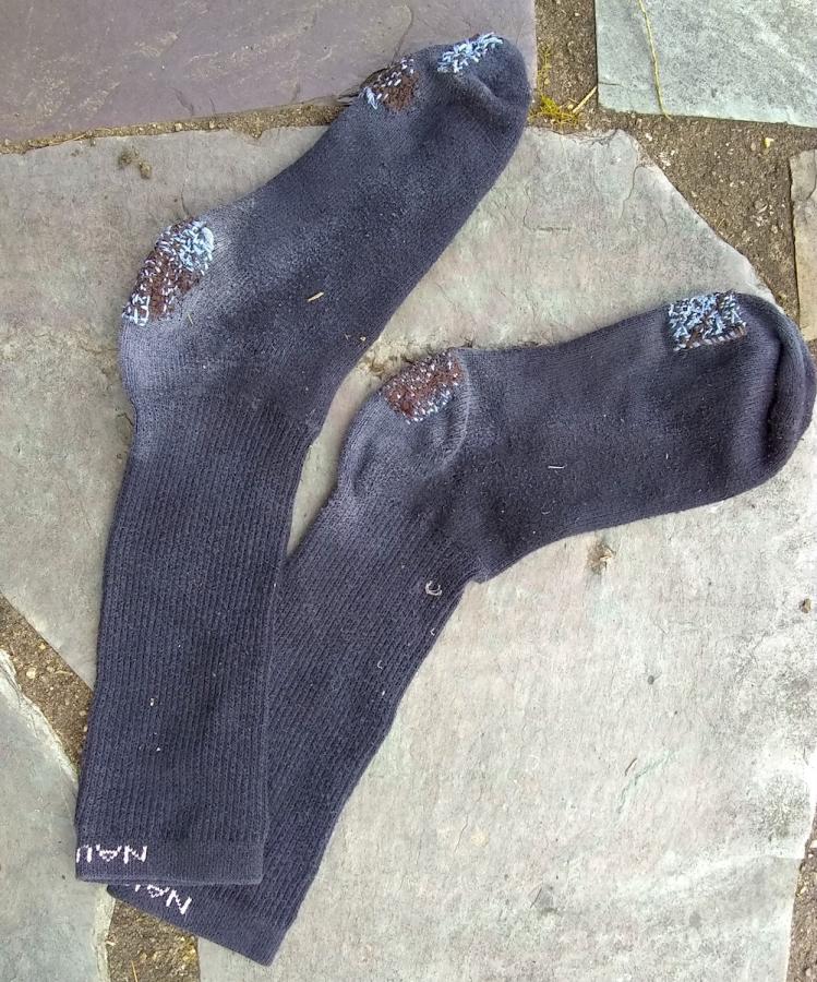 blue and brown darns on heels and toes of a pair of black socks