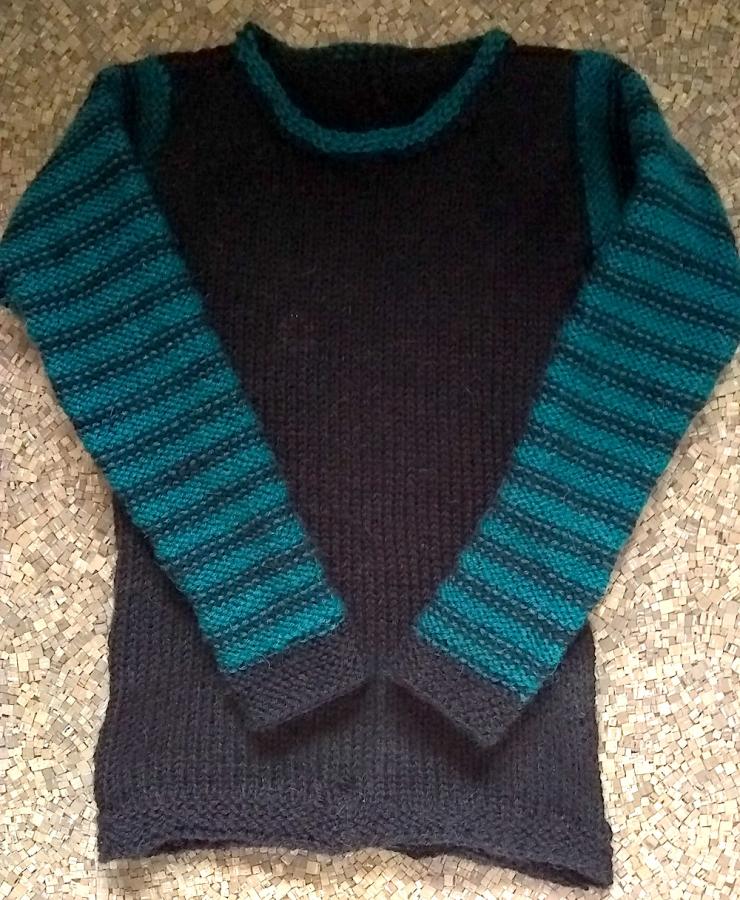 Black sweater with black and green striped sleeves and green trim at neck, shown lying flat on linoleum floor