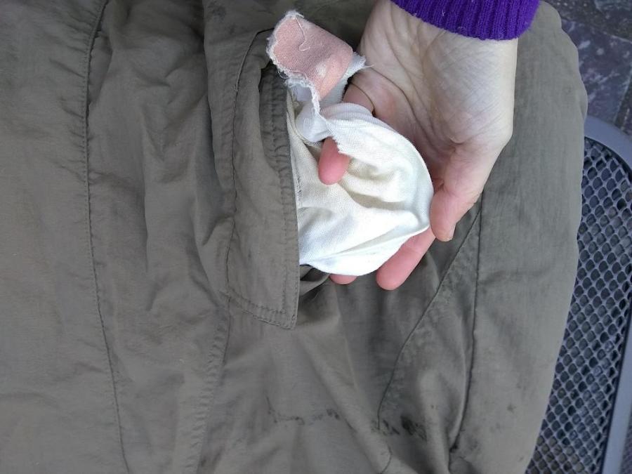 part of olive jacket showing inside out pocket lining and hand showing holes in pocket lining