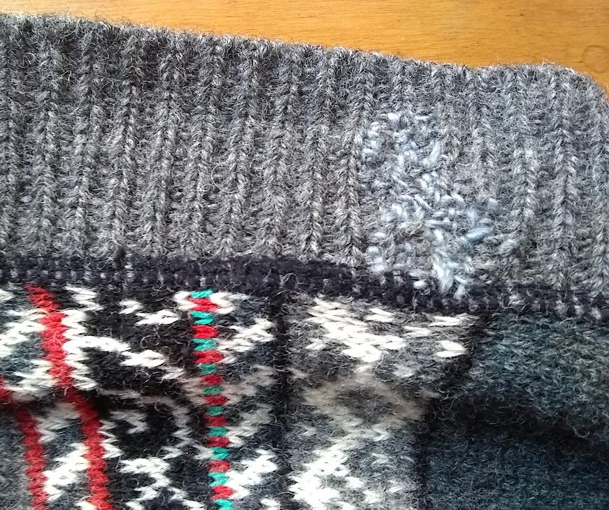 CLoseup of ribbed neck of gray/multi sweater, with somewhat visible lighter gray darns at neck ribbing